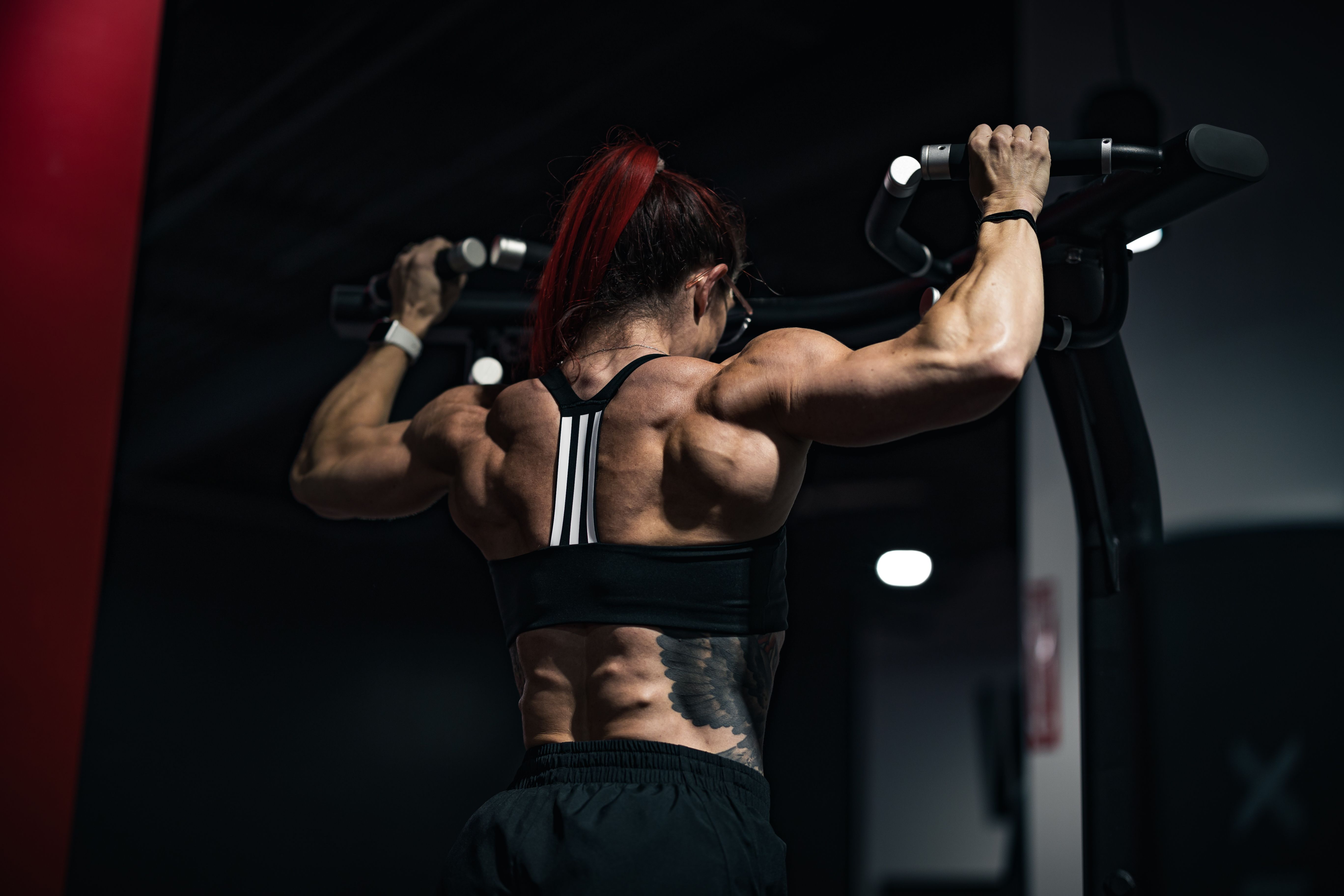 Woman performing a pull-up on a gym bar, muscular back visible