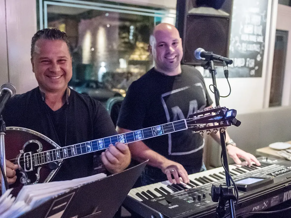 The Greek Night band on bouzouki and keys, smiling at the front window of The Phoenix