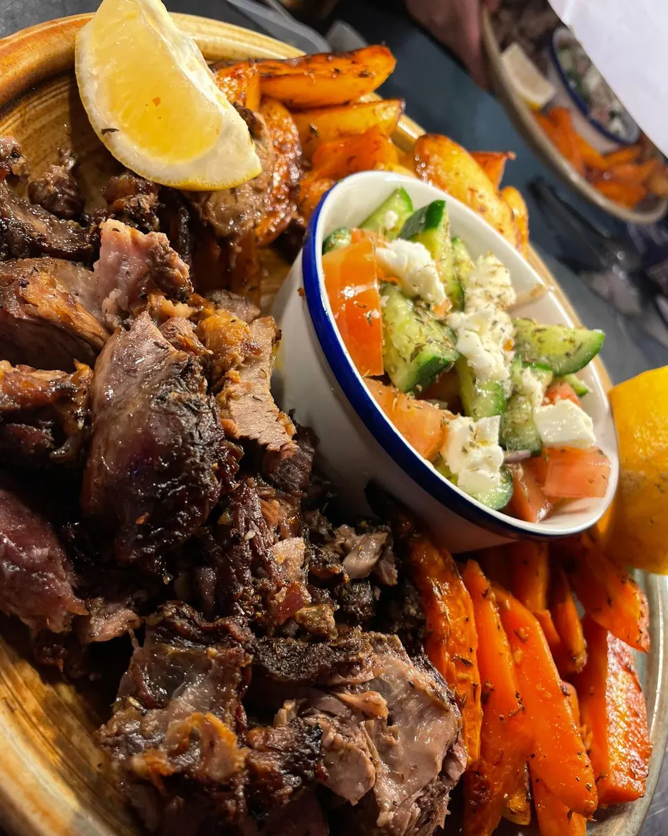 Slow-roasted lamb shoulder with roast potatoes and a Greek salad to share