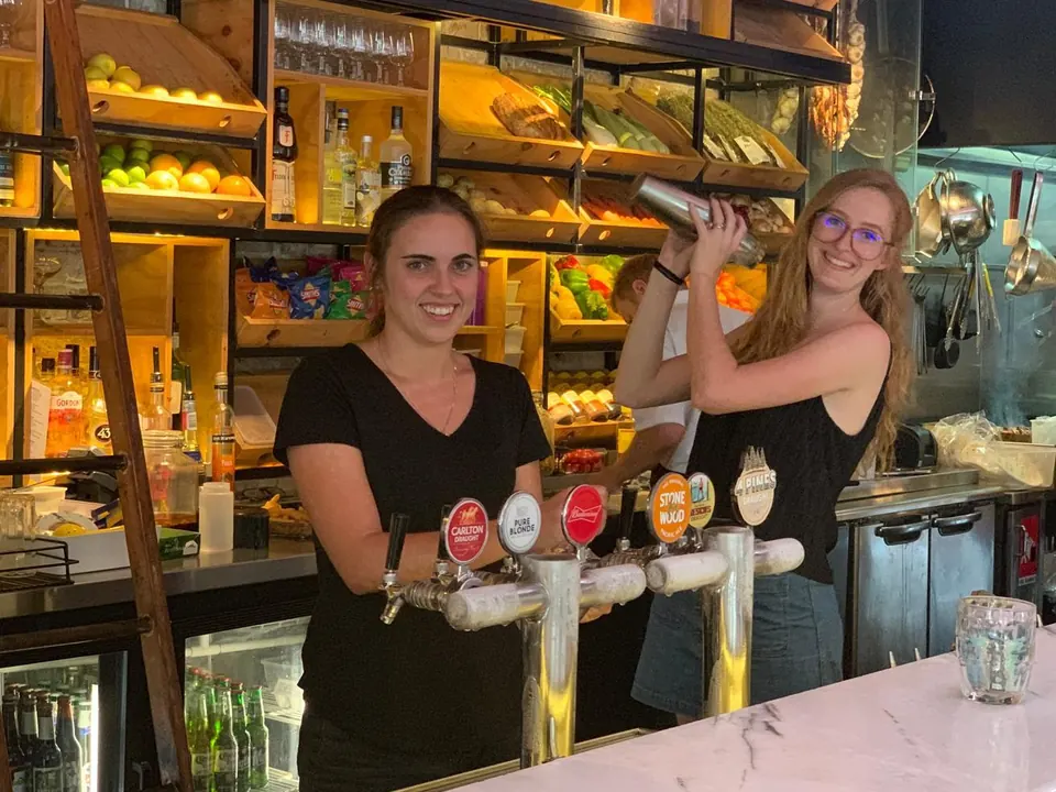 Two bartenders smiling behind the marble bar and beer taps