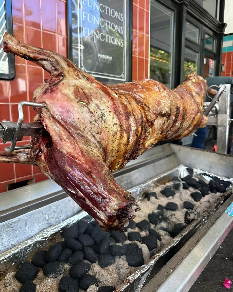 A whole lamb turning on a charcoal spit outside The Phoenix