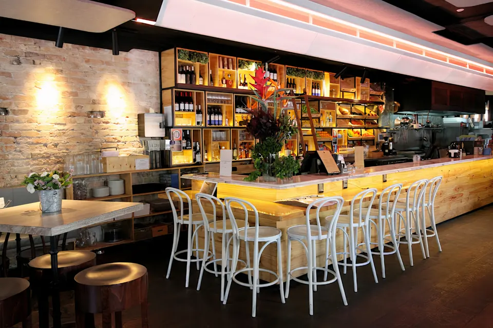 The Phoenix's main bar in daylight with white bentwood stools and flowers on the marble bar top