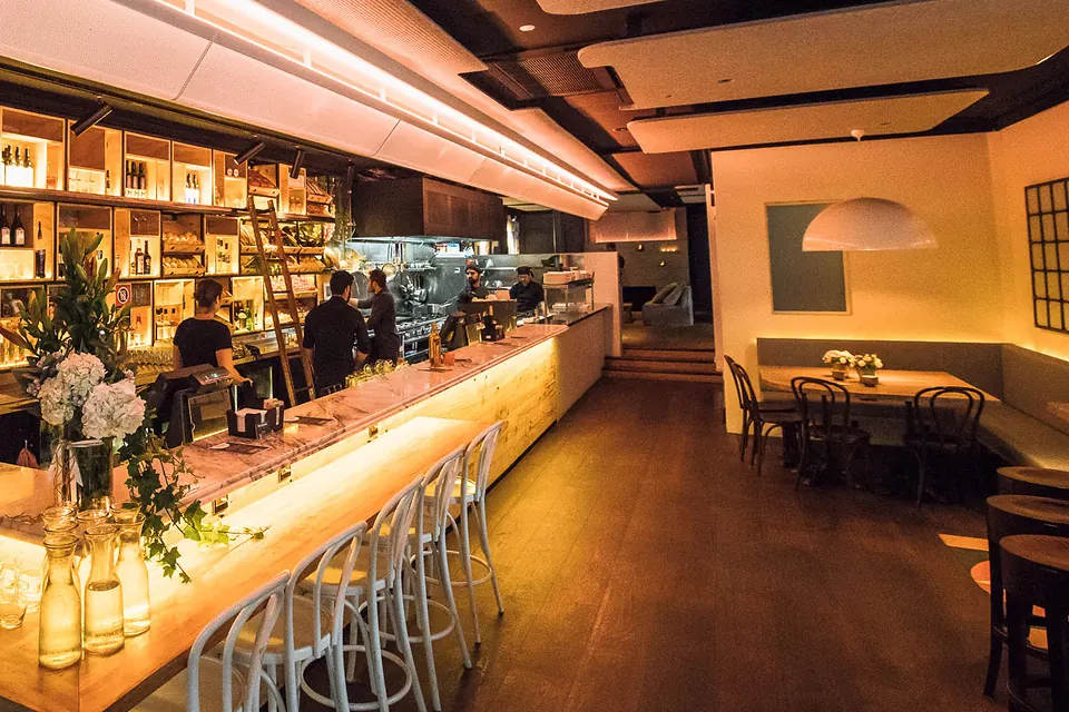The Phoenix's long marble bar set for the evening, a row of white bentwood stools waiting and the team behind the bar