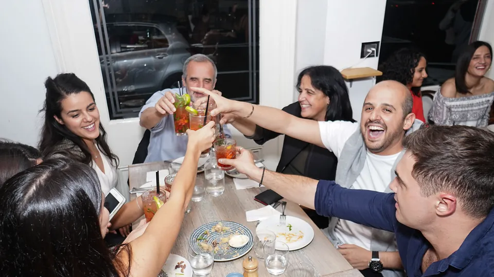 Friends raising glasses over Greek share plates at The Phoenix, Woollahra