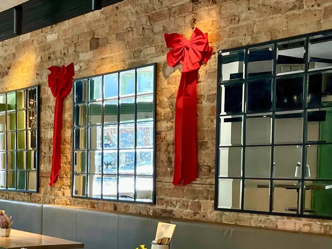 The dining room dressed with red Christmas bows over the windows
