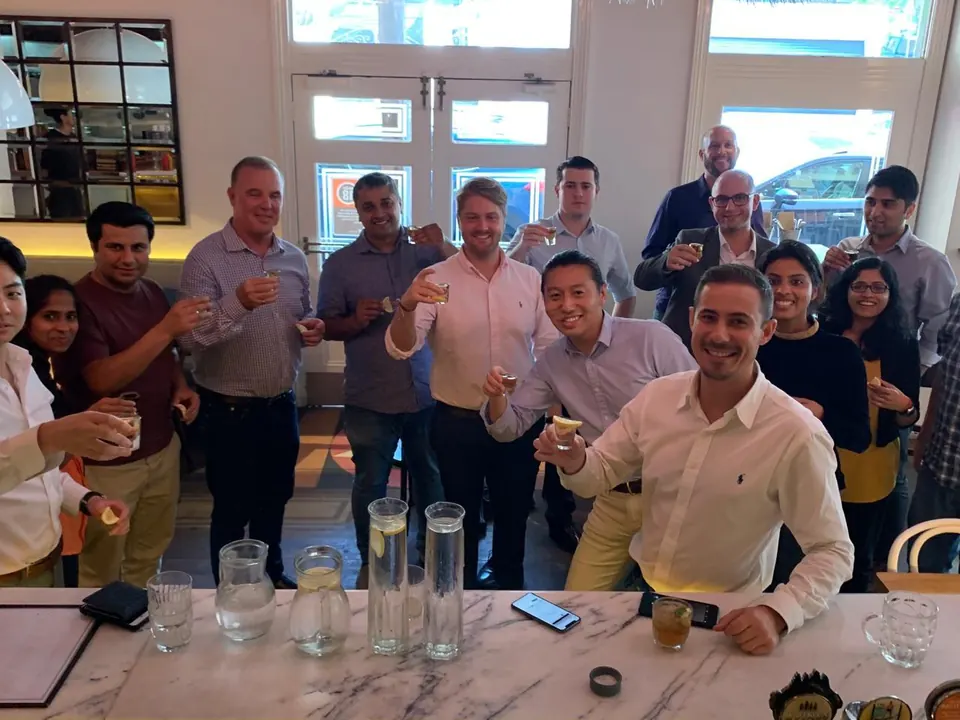 A work group raising glasses at the marble bar during a corporate function