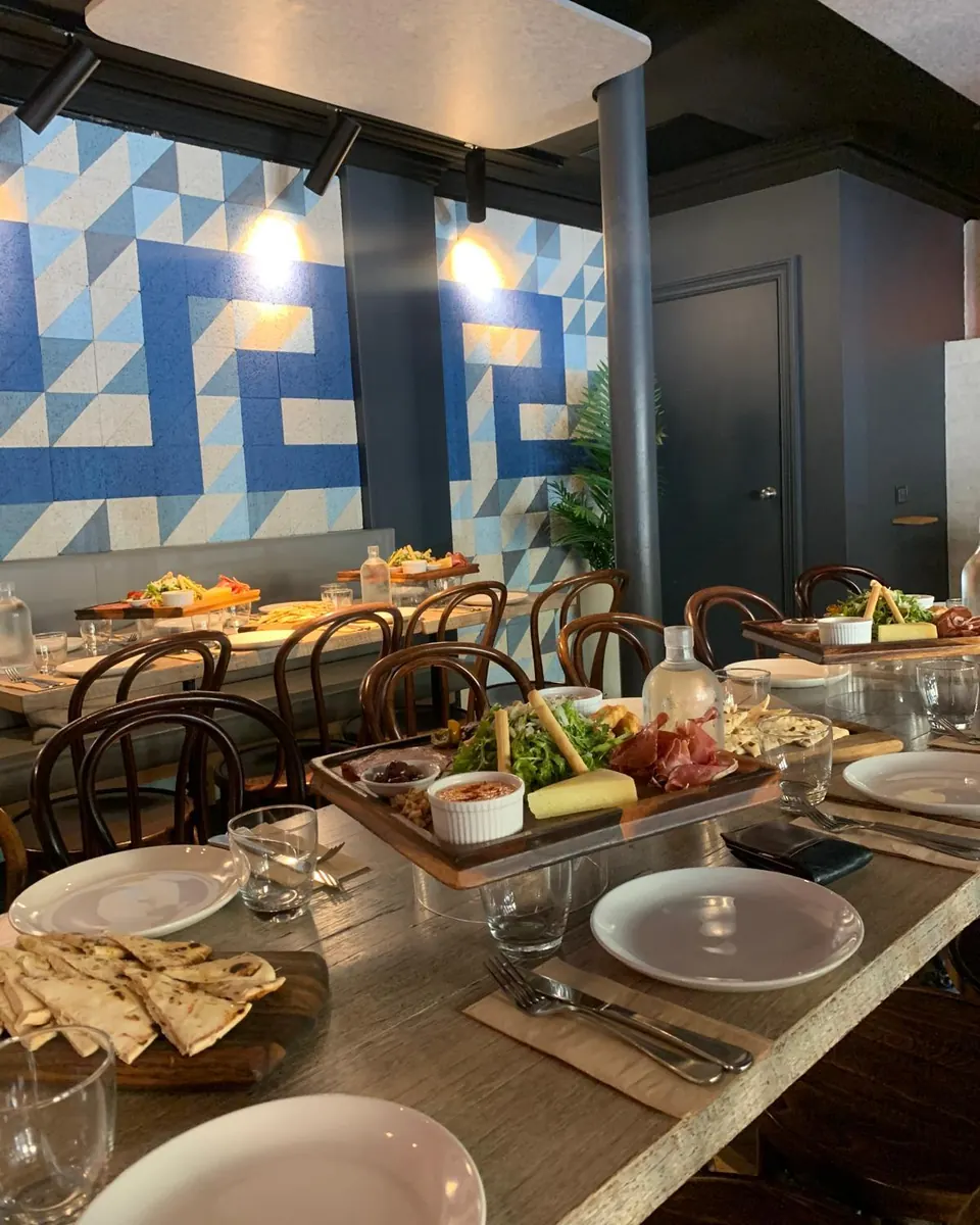 Share boards set on a long table beneath the blue and white Greek-key wall in The Nest