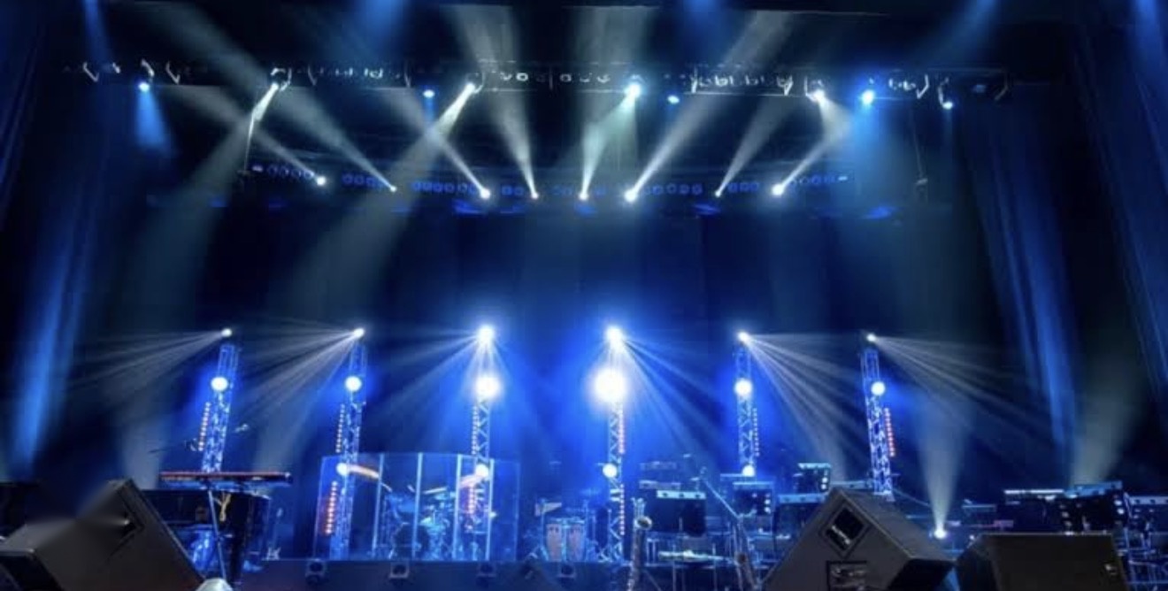 Wide stage with blue light beams and lighting truss towers