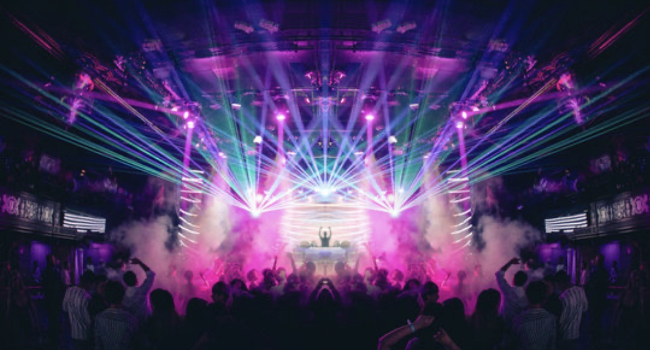Nightclub with laser lighting, a DJ booth and a packed dance floor