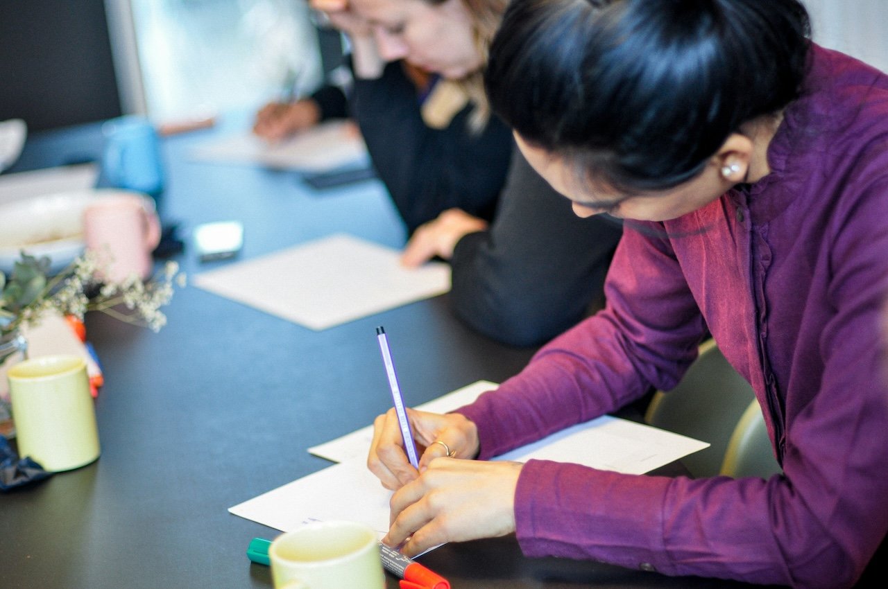Workshop participants writing notes at a shared table