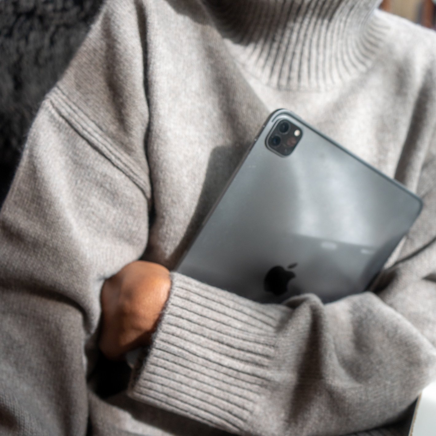 Person in a grey sweater holding a tablet