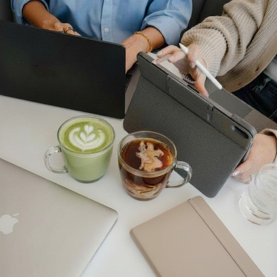 Two people working on tablets over coffee
