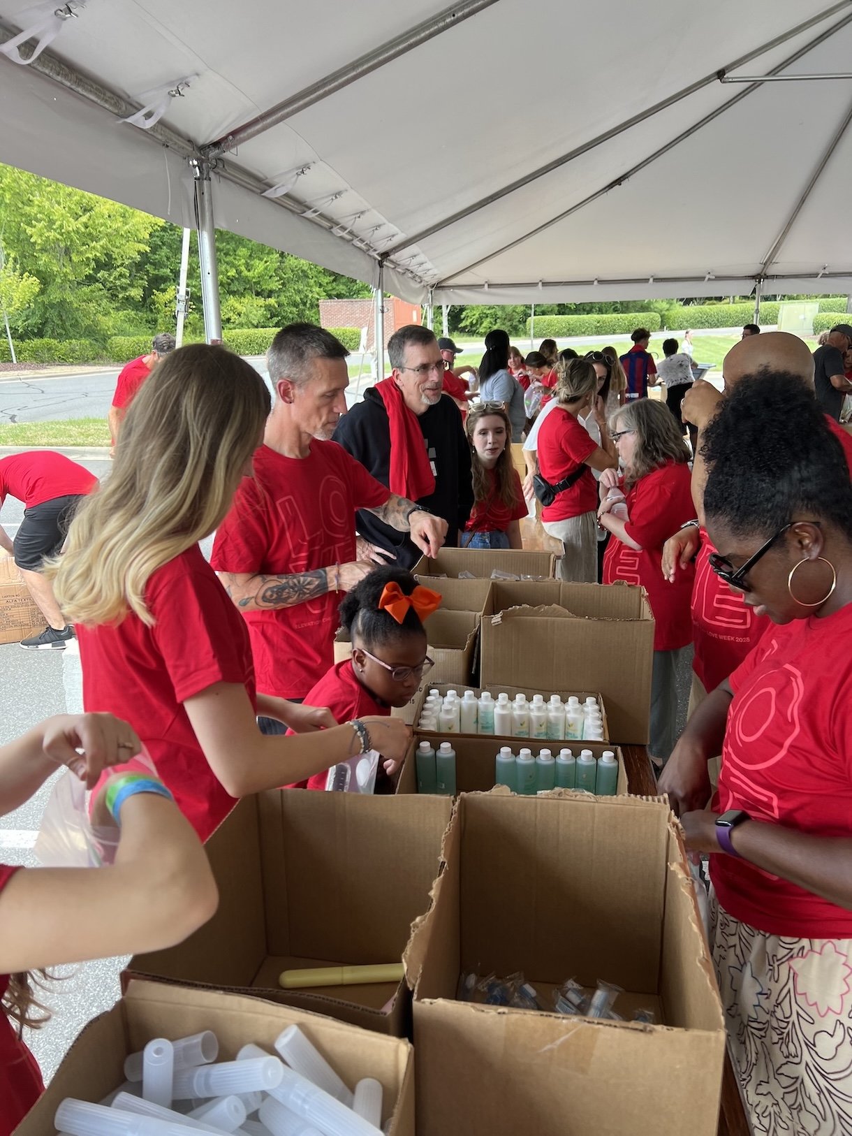 Volunteers in red shirts packing boxes at a community event