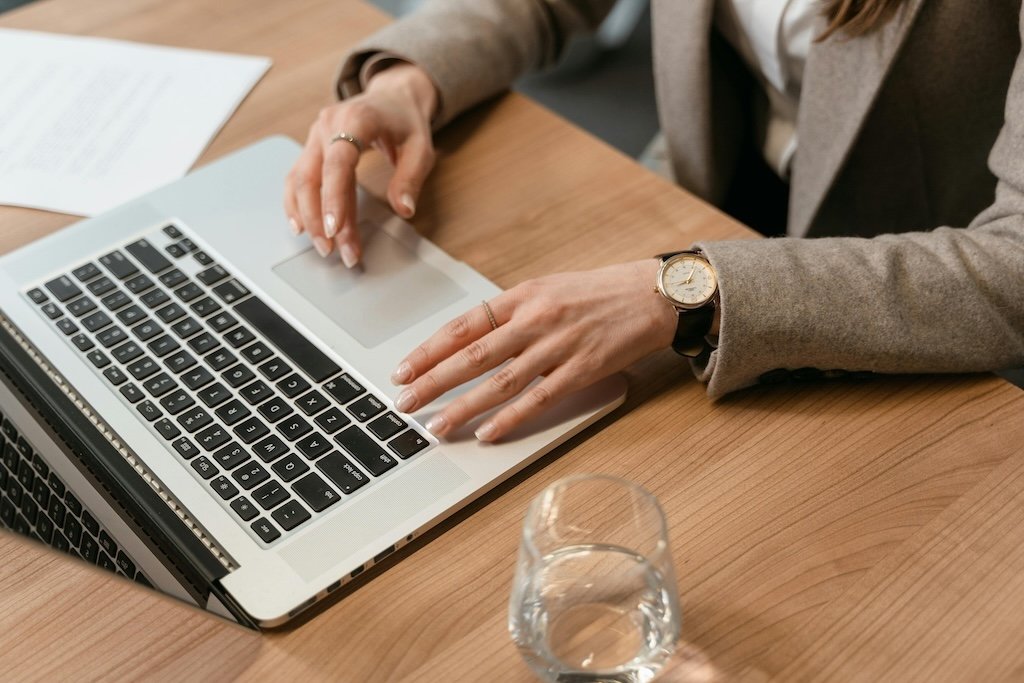 Hands typing on a laptop at a desk