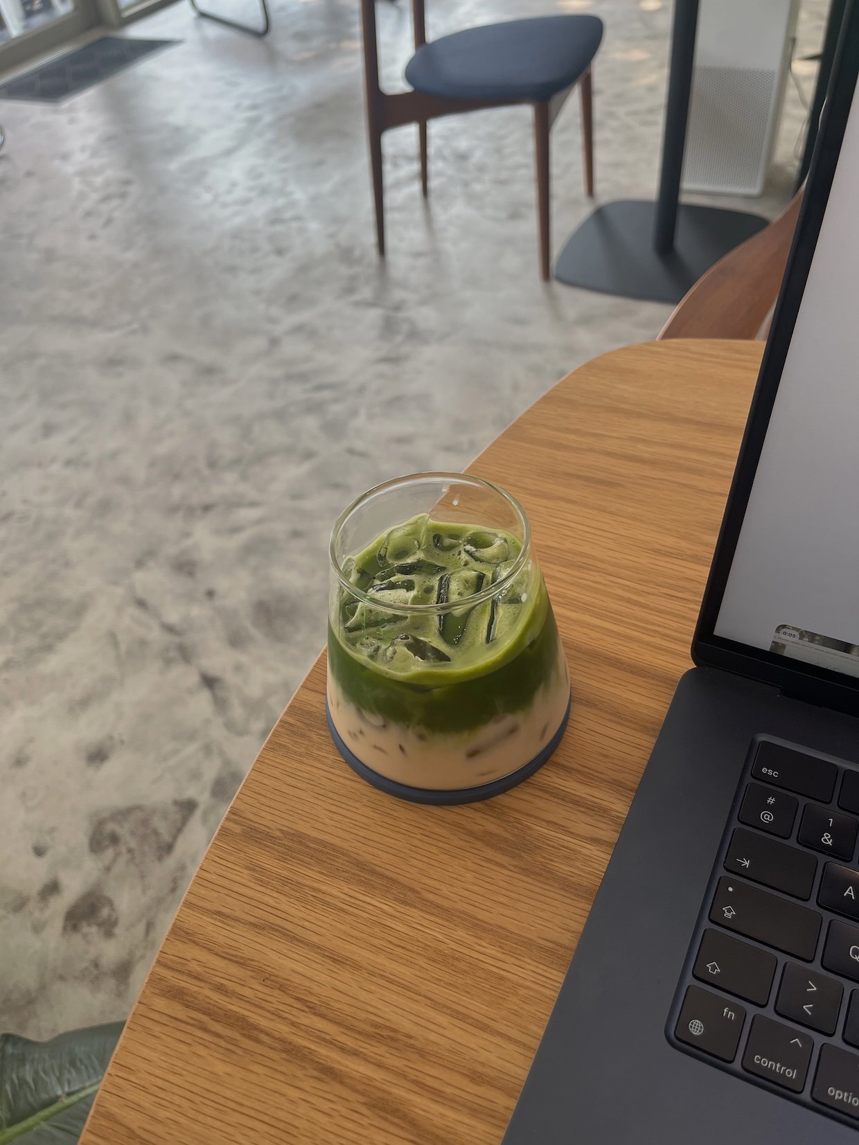 Iced matcha next to an open laptop on a wooden table