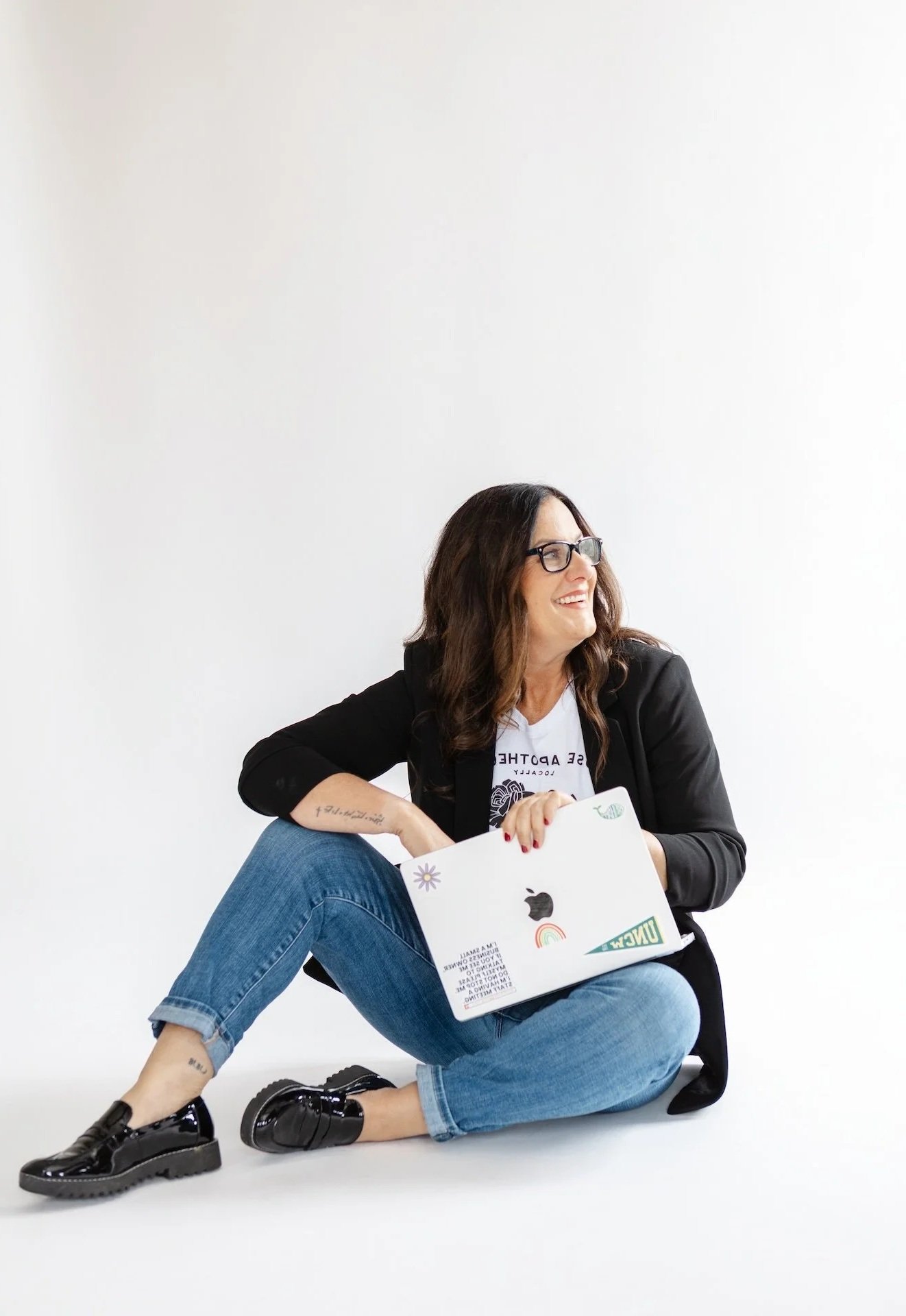 Sarah Price sitting on the floor with a laptop, smiling