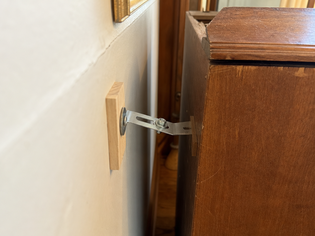 An anti-tip bracket securing a tall bookcase to a wall stud