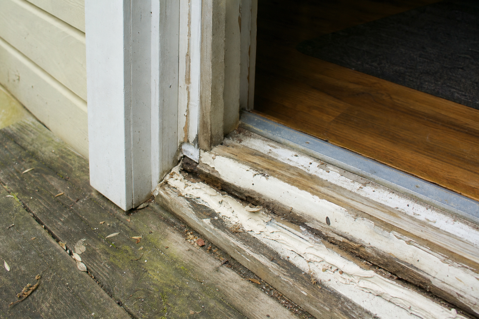 Caulk smeared over a rotted door sill with no flashing underneath