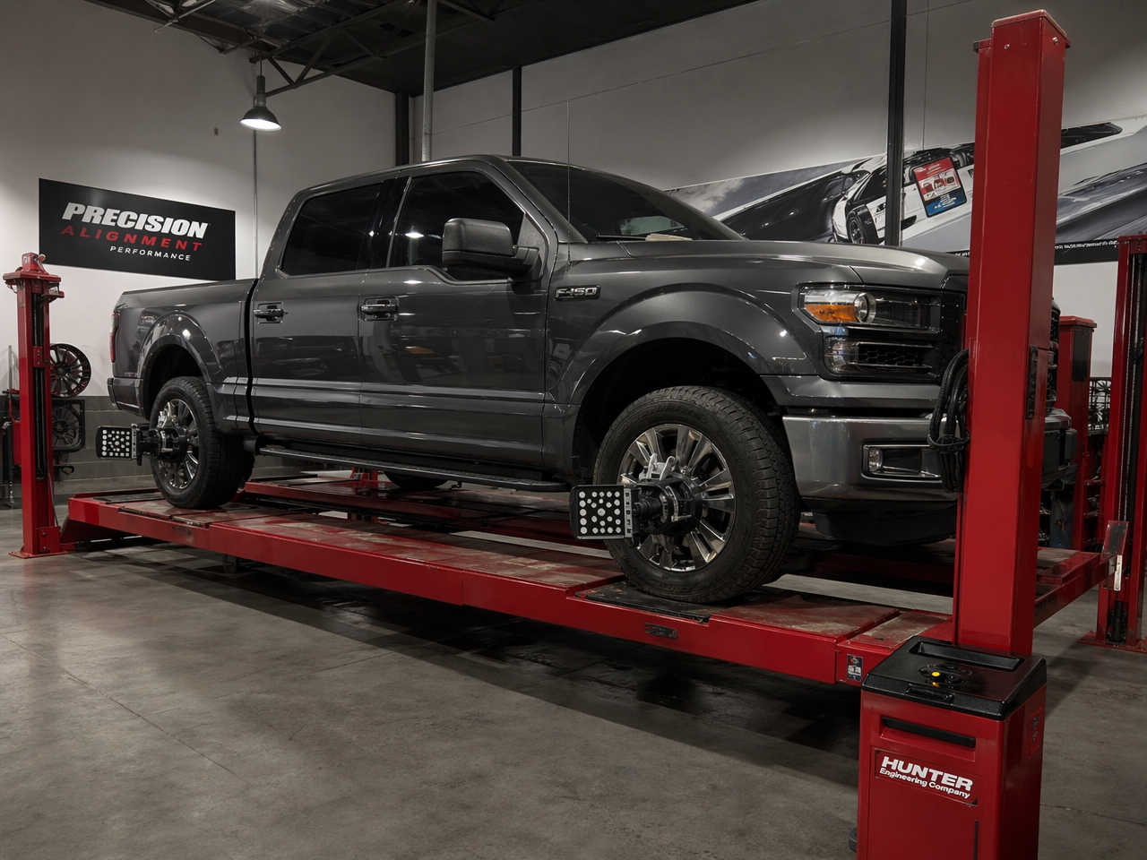 Pickup truck on alignment rack with laser alignment targets on all four wheels