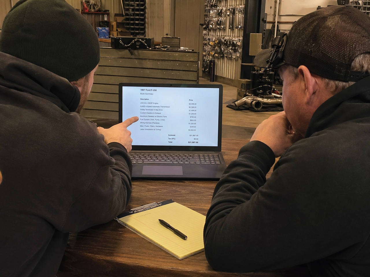 Customer and shop owner sitting at desk reviewing a build quote together