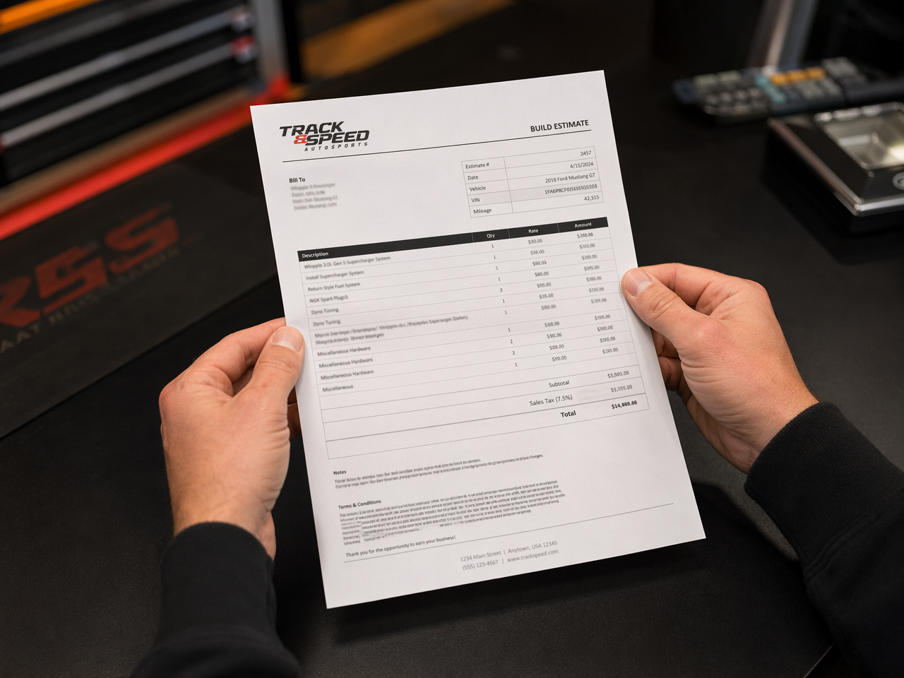 Hands holding a printed automotive build quote with line items visible