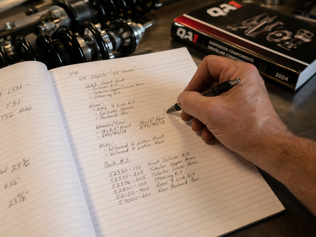 Hand writing build notes and specs in a shop notebook on a workbench
