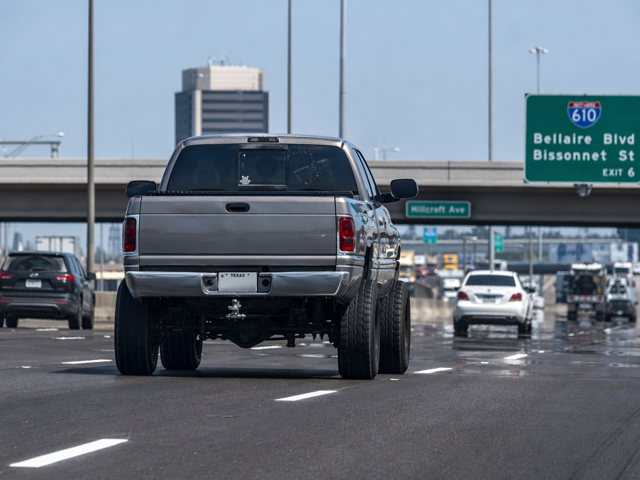 Lifted truck driving on Houston highway with heat shimmer on pavement