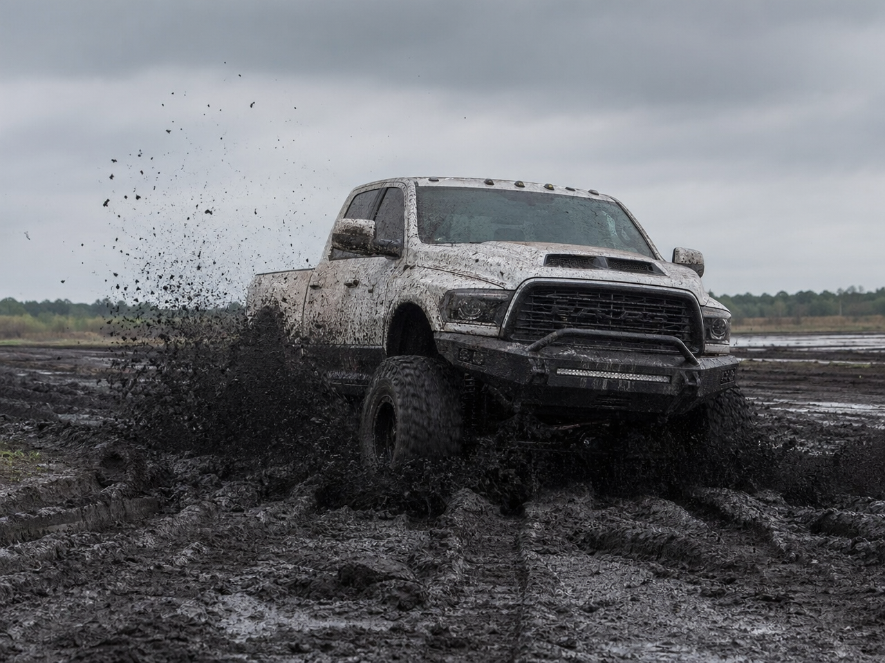 Lifted pickup truck pushing through deep East Texas black gumbo clay mud with rooster tails off tires