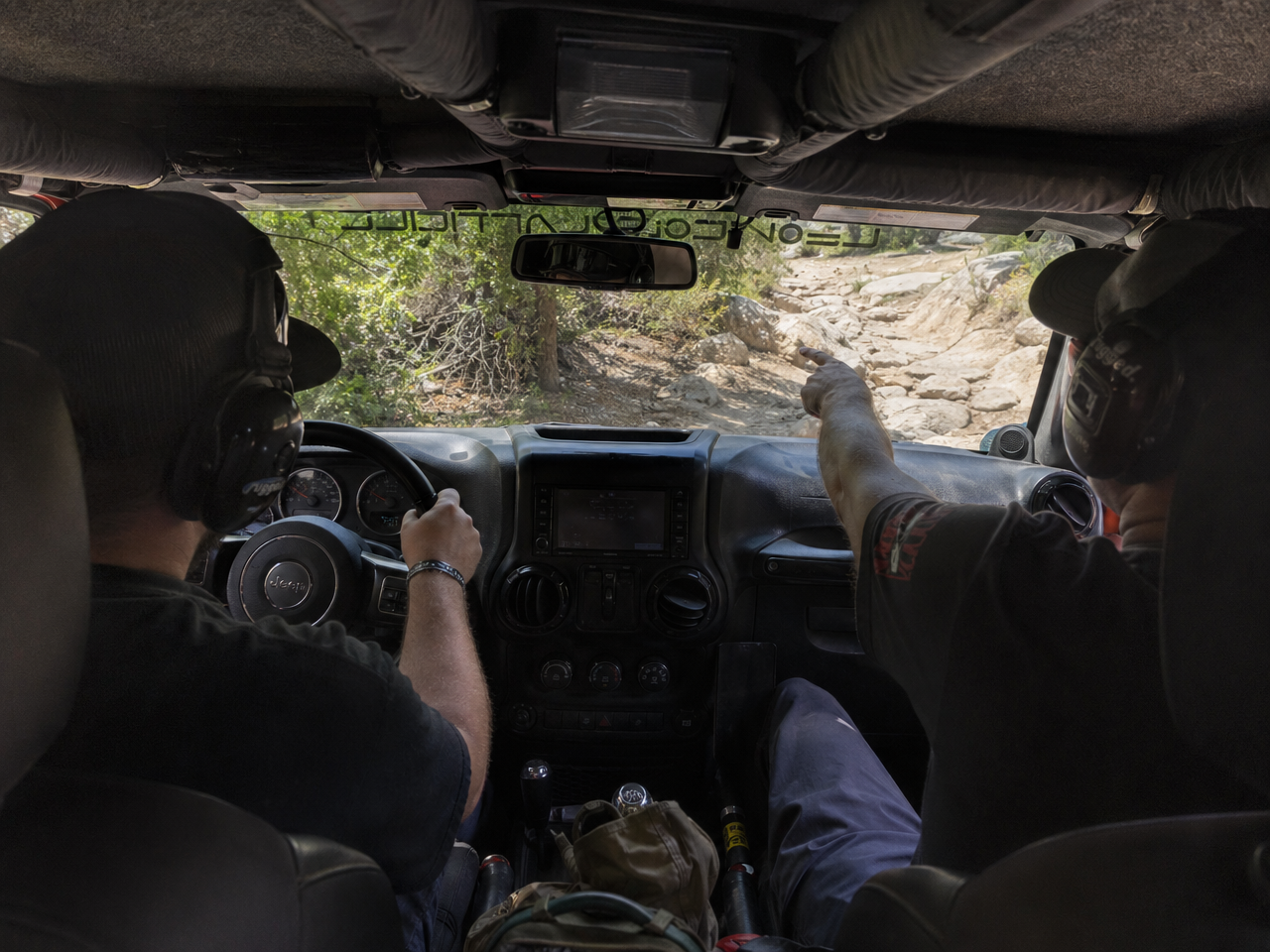 Trail guide in passenger seat pointing out terrain line to driver during active trail session