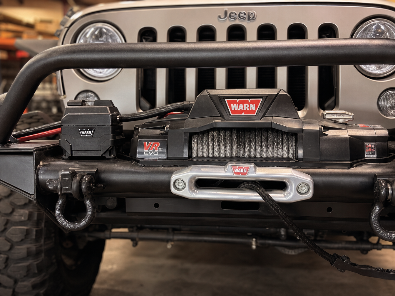 WARN winch mounted in steel tube bumper on JL Wrangler with clean wiring in shop bay