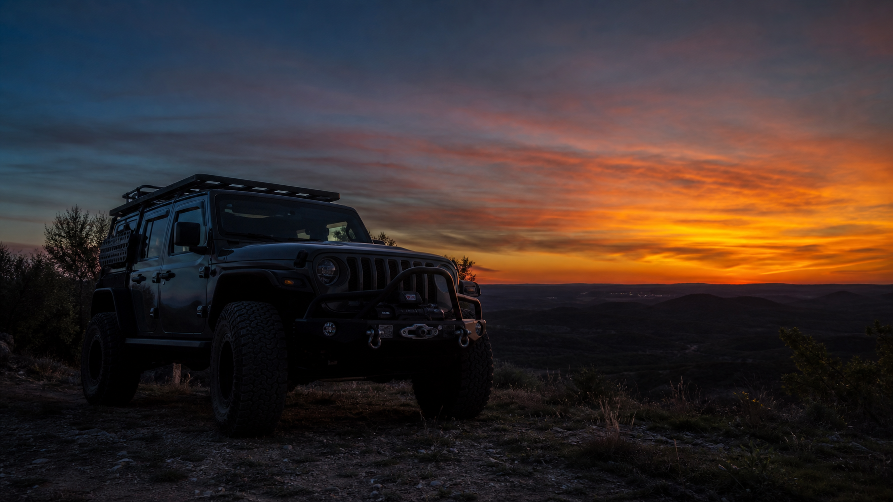 Fully armored Jeep Wrangler JL at trail overlook at dusk with winch and rock sliders visible