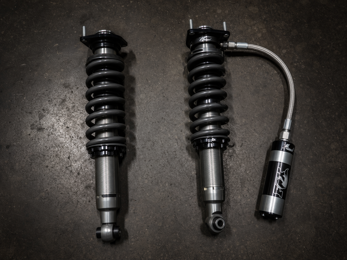 Standard coilover versus remote reservoir coilover side by side on dark shop floor
