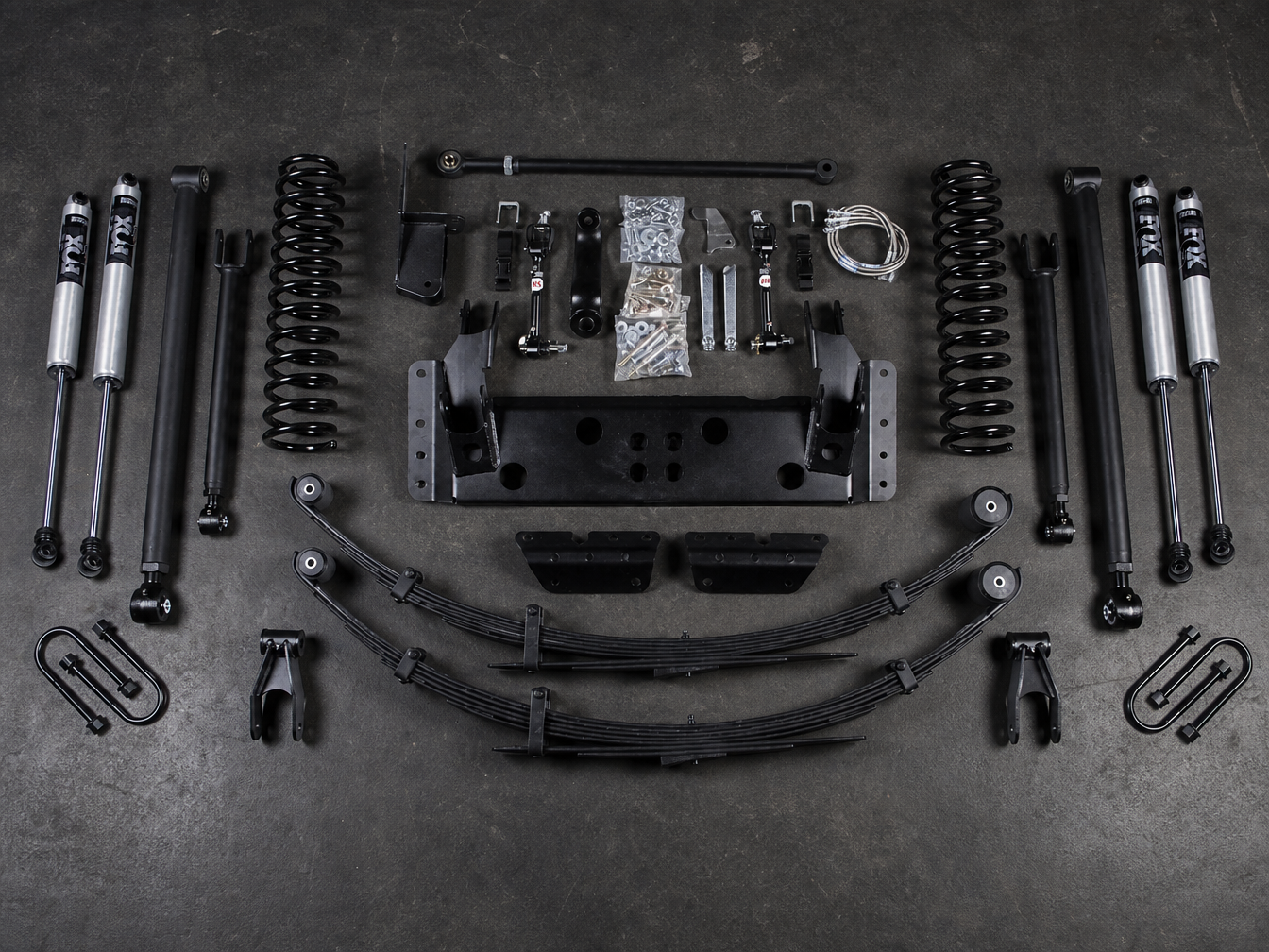 Complete long arm suspension kit components laid out on shop floor before installation on a Jeep Wrangler