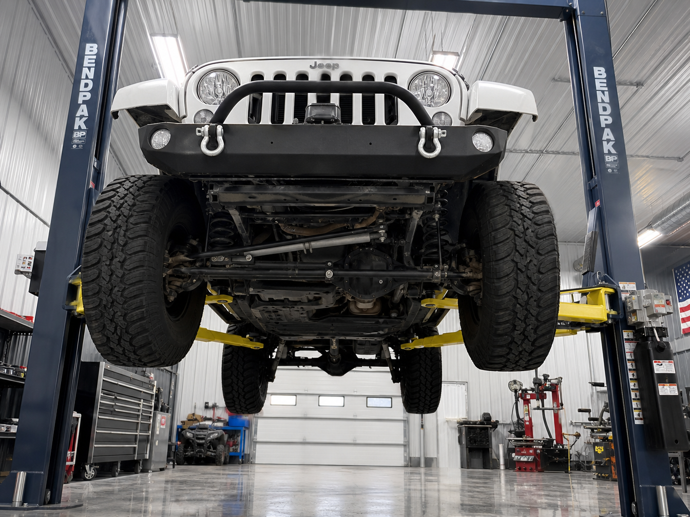 Jeep Wrangler JK on 2-post lift with front axle and steering components fully visible for death wobble inspection