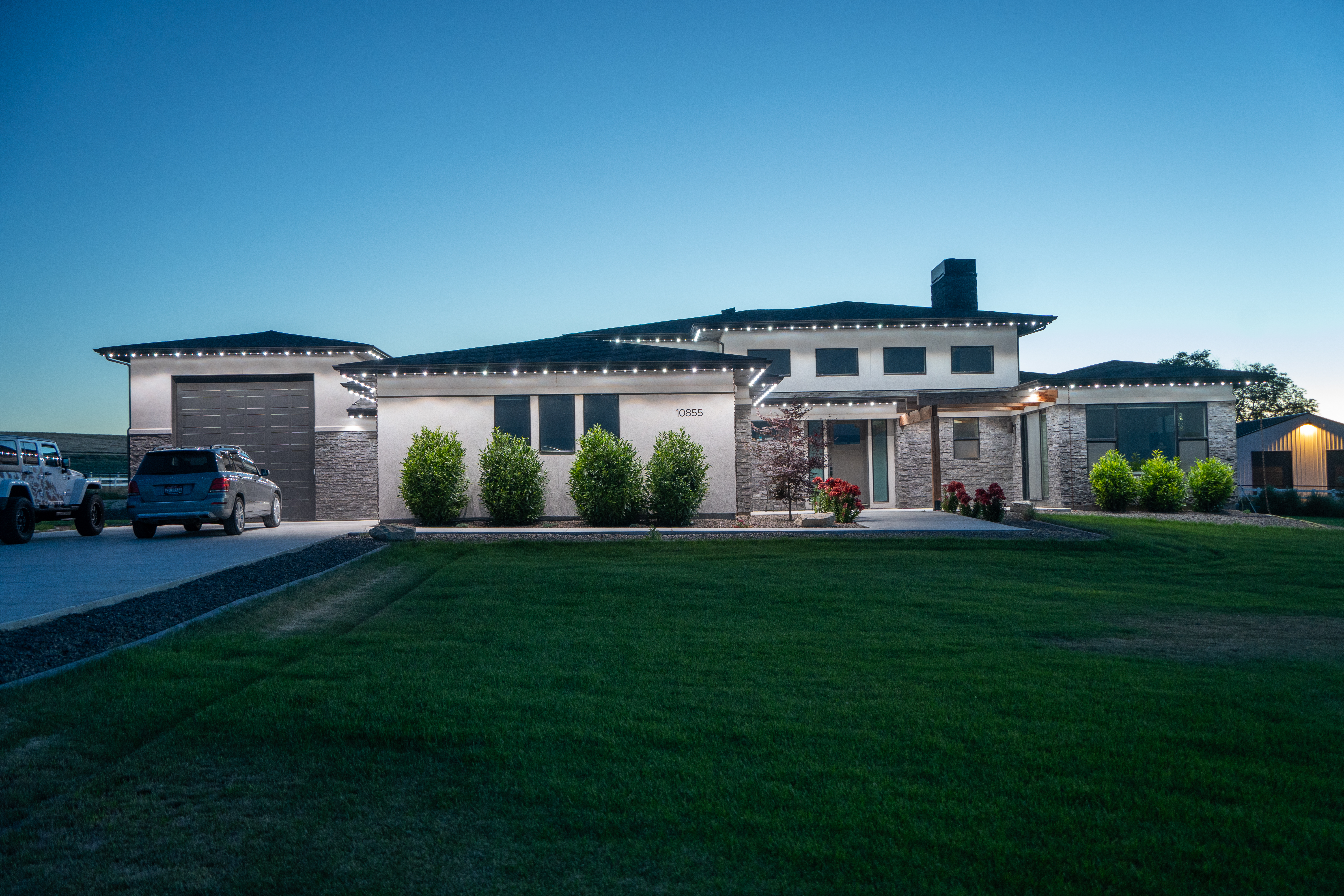 Modern home with white permanent lights on the roofline at twilight