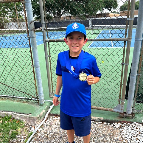 Young Zenniq Academy tennis player holding a medal after purposeful practice and player development