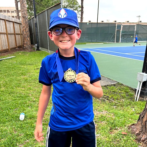 Young Zenniq Academy tennis player holding a medal in a structured tennis training environment