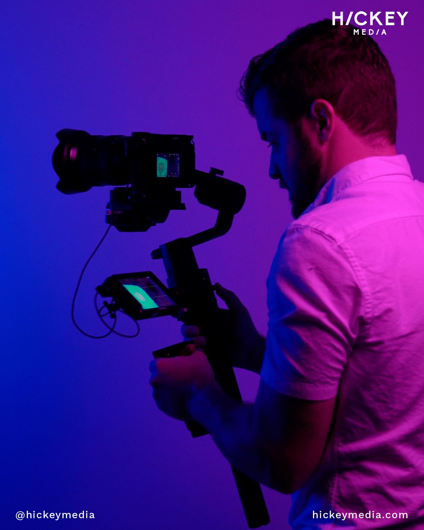 Blake holding a camera on a gimbal under blue and magenta light