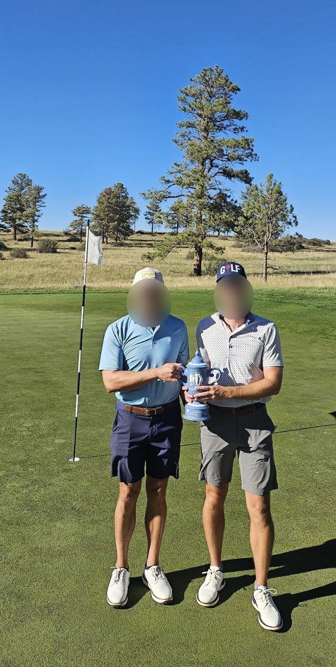 The player and his partner holding the match play trophy, faces blurred