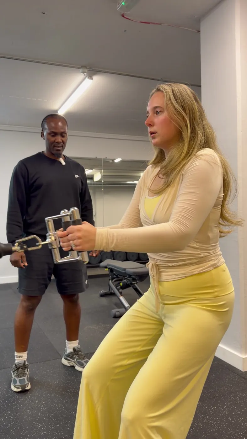 Coach guiding a client through a cable exercise