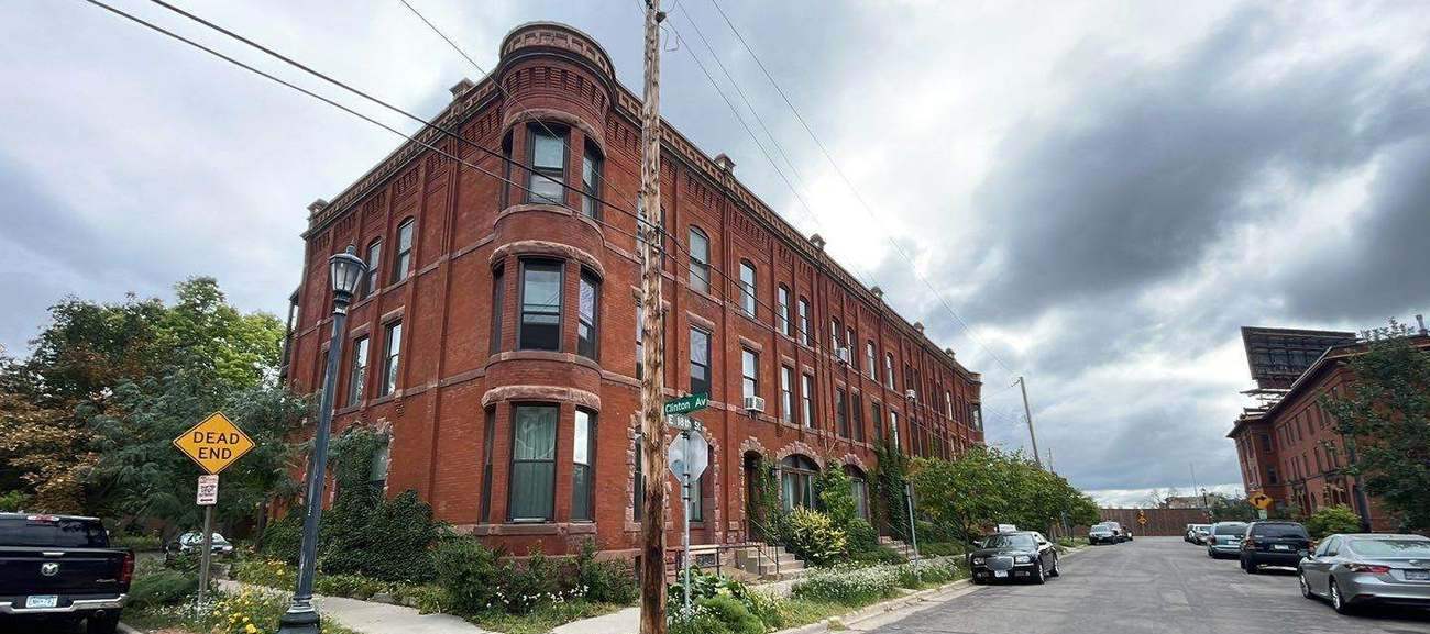 Historic red-brick Romanesque Revival apartment building on East 18th Street in Minneapolis, photographed during a Repair King roof project, September 2023