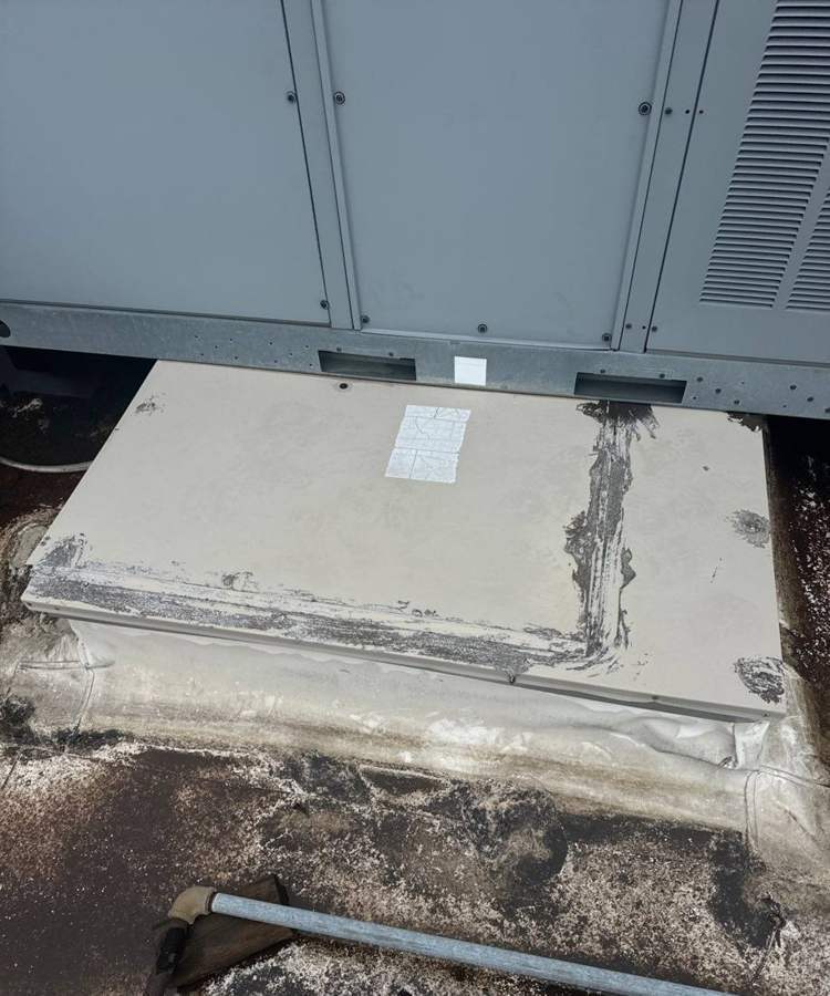 Patched, cracked membrane at the base of a rooftop unit on the Bloomington Lincoln roof, July 2024