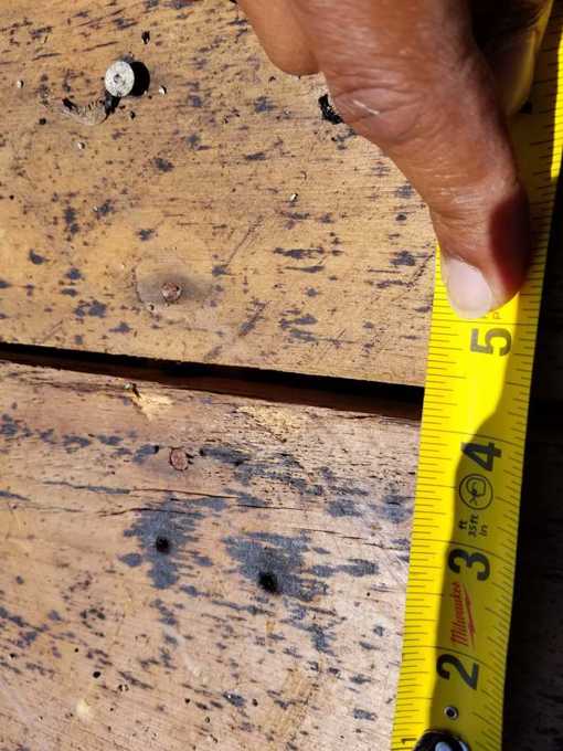 Tape measure across a gap between old deck boards after tear-off at Red Rock Lodge