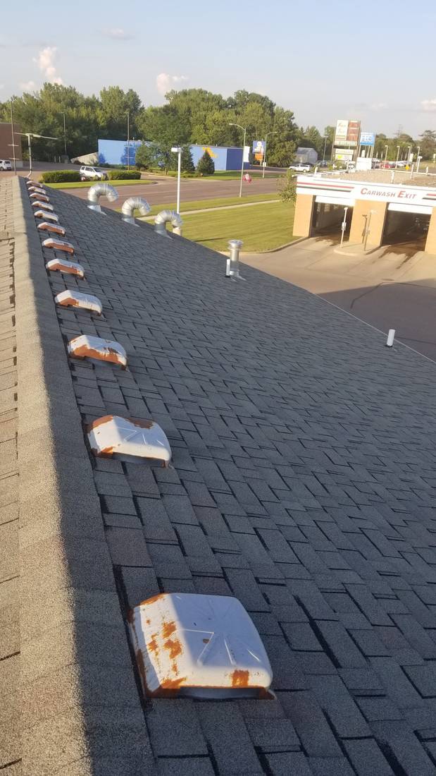 Row of dented, rust-streaked box vents along the ridge of Mega Coin Laundry in Fairmont, MN