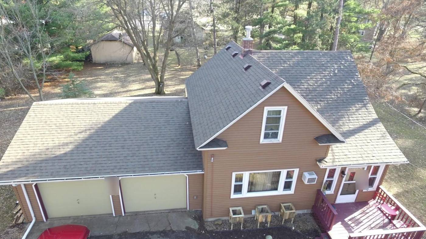 Drone view of a story-and-a-half home in Hinckley, MN after Repair King's tear-off: new shingle roof and box vents, new tan lap siding and white gutters