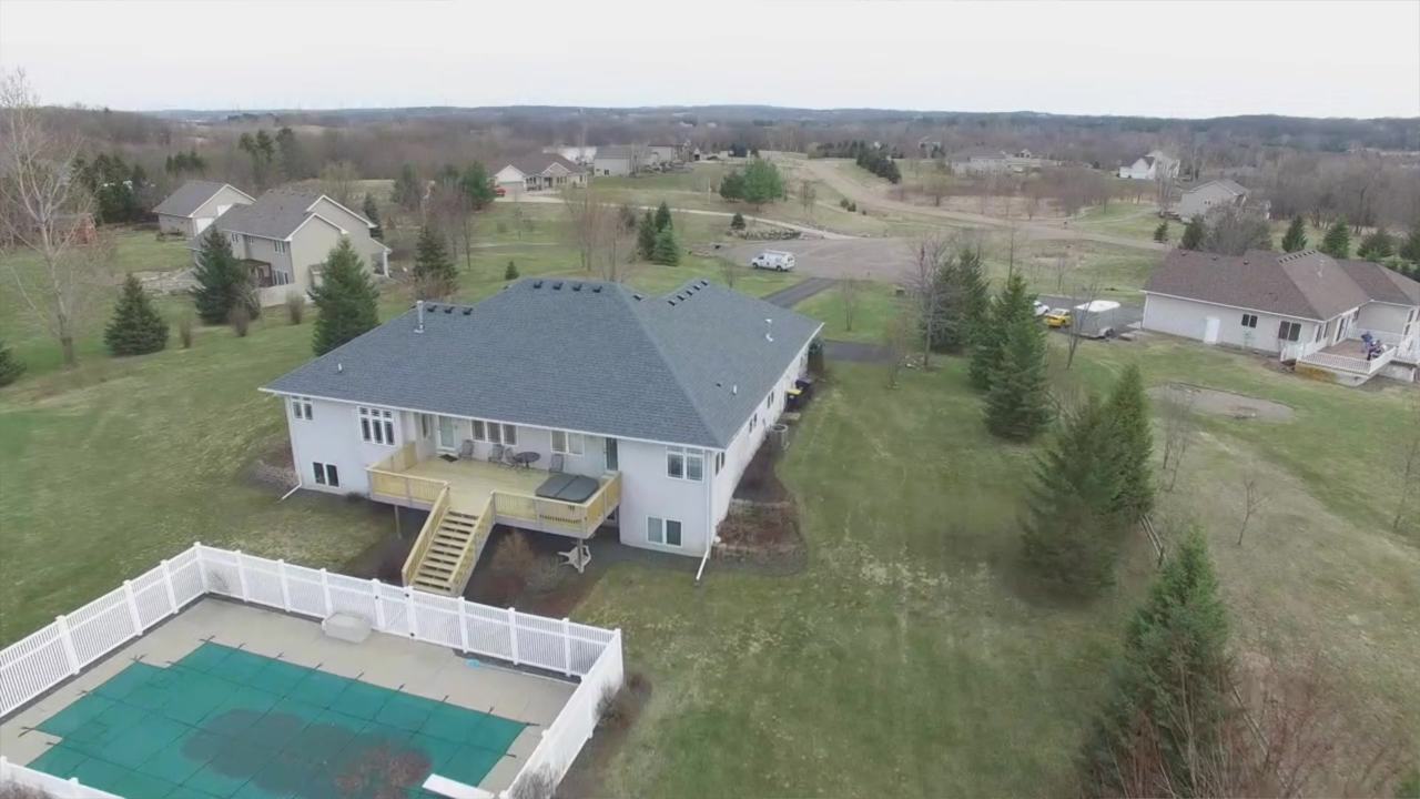 Drone view of the Ward family's walkout rambler with a Lakeville address: new gray shingle roof, rebuilt wood deck and stairs, and the white vinyl pool fence, spring 2019