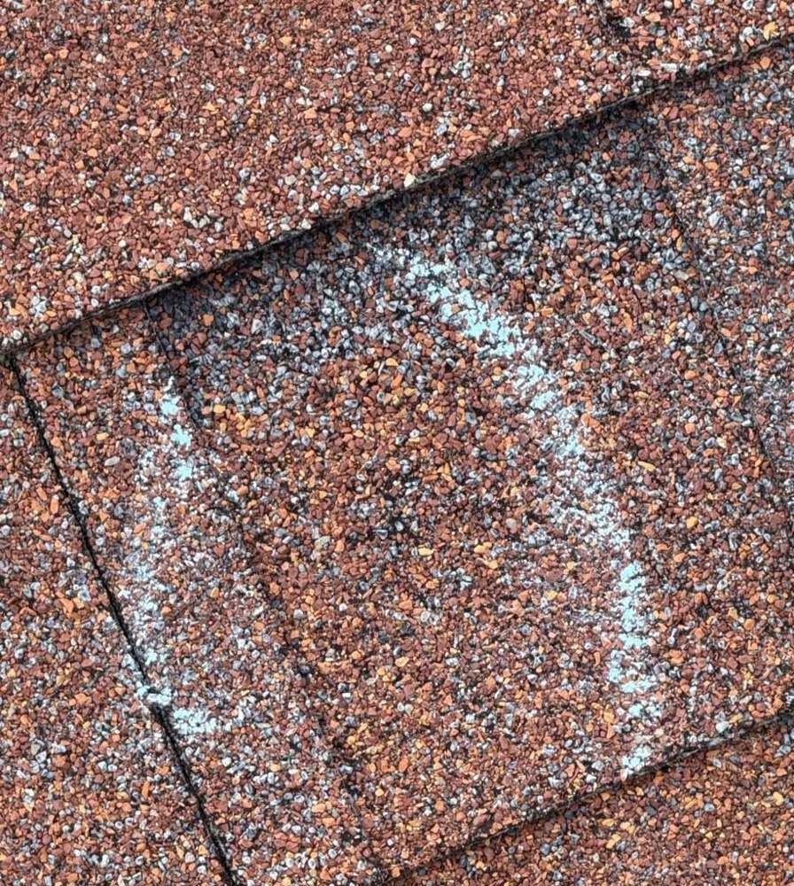 Chalk-marked hit on reddish-brown shingles during a Chanhassen roof inspection, September 2025