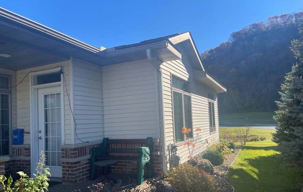 Vinyl-sided single-level home in Lake City, MN with a wooded bluff behind it, photographed by Repair King in October 2021