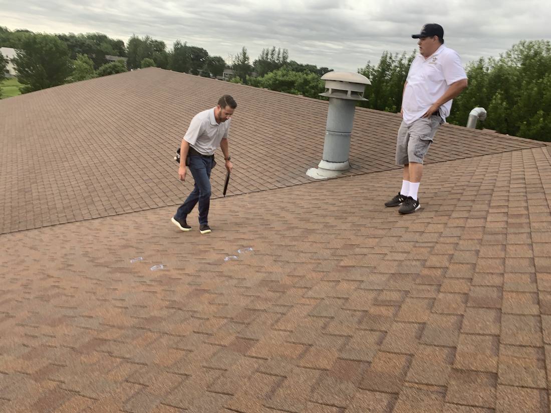 Two Repair King inspectors walking the brown shingle roof of Heritage Estates in Dodge Center, MN