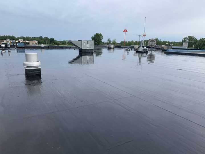 Wide view of the black rubber flat roof with rooftop units and exhaust fans at Eide Chrysler Dodge Jeep Ram in Pine City, MN, July 2019